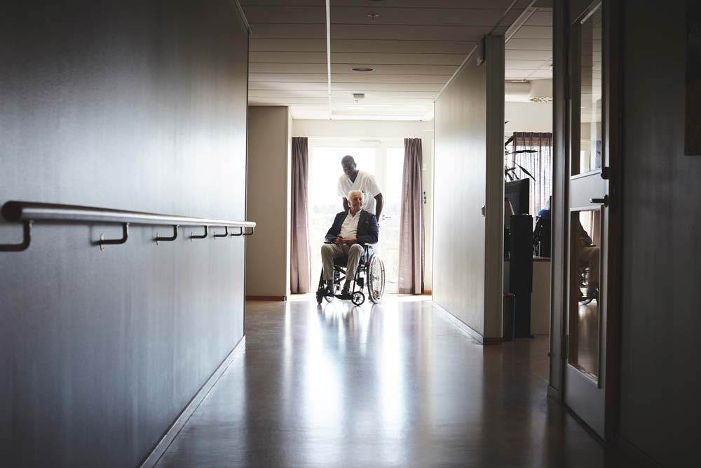 En äldre man i en rullstol i en korridor.