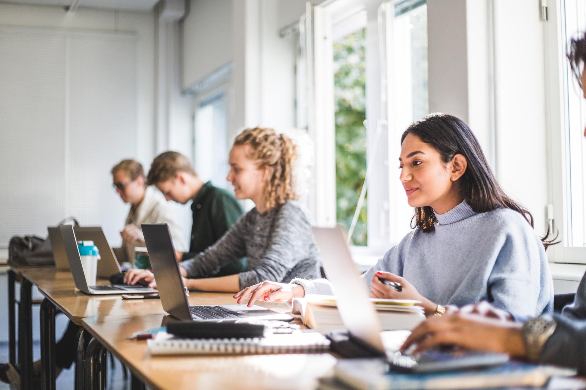 Tre studenter som sitter vid sina datorer